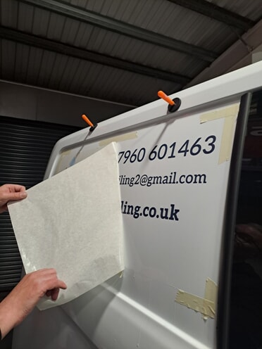 An image showing someone revealing the new vehicle graphics on the side of the white van